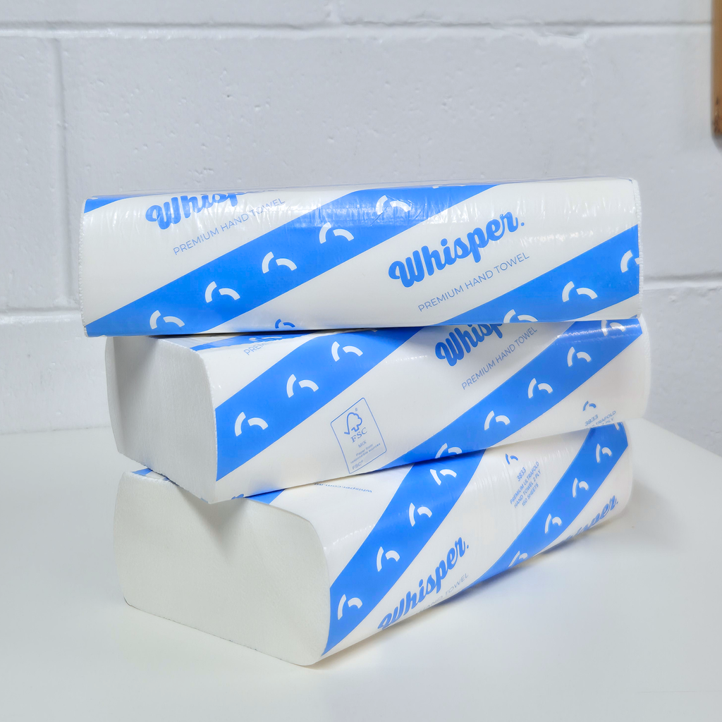 Premium Ultrafold Hand Towel 2ply, Whisper 3833, Blue stripe packaging on white background, white papaer hand towel product, white brick background, three stacked on top of each other