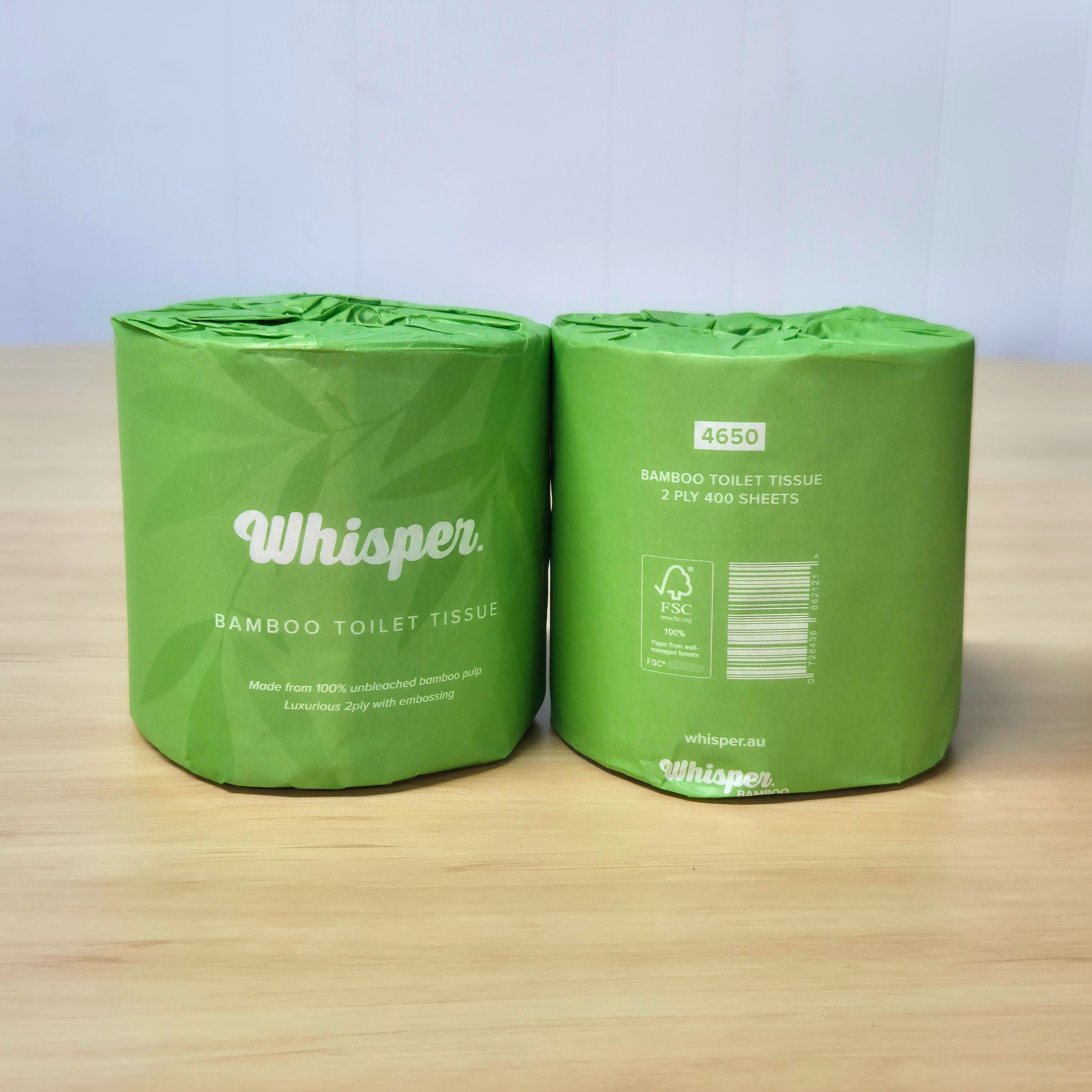 4650 whisper bamboo toilet tissue, toilet paper, made from 100% unbleached bamboo pulp, 2ply, green paper wrapper with leaf shadows, on white background, on table
