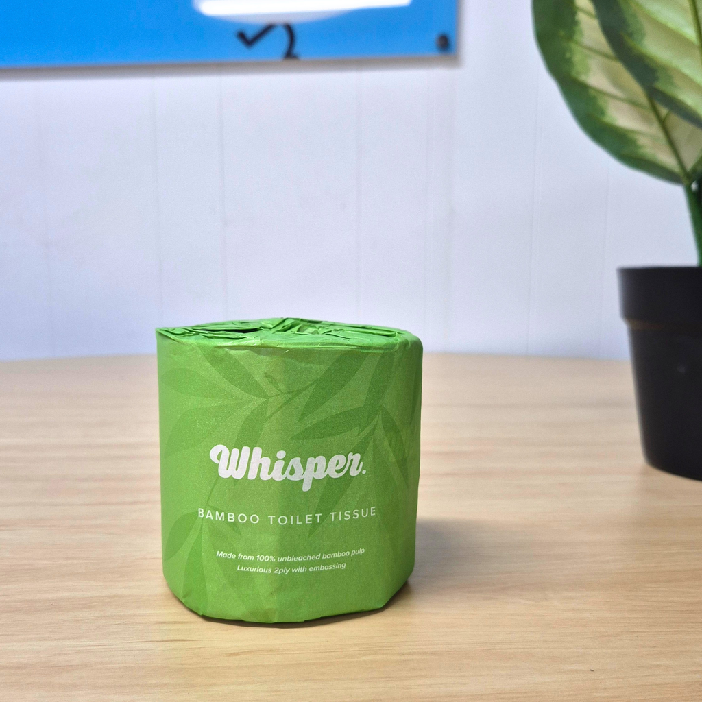 4650 whisper bamboo toilet tissue, toilet paper, made from 100% unbleached bamboo pulp, 2ply, green paper wrapper with leaf shadows, on table with plants