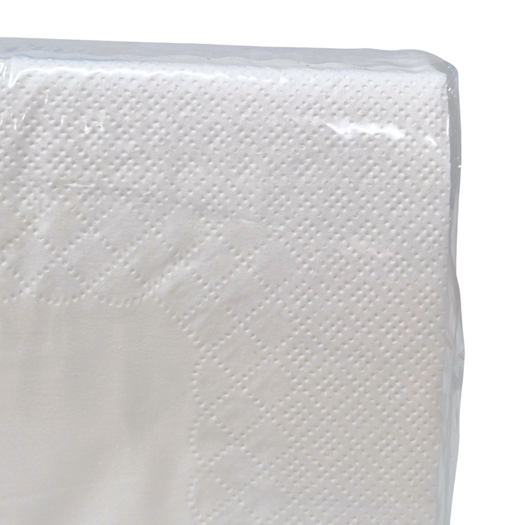 A pack of Whisper brand 2-ply white luncheon napkins in a clear plastic wrapper with a green label showing white cutlery icons and product details. Dot embossing and QT fold.